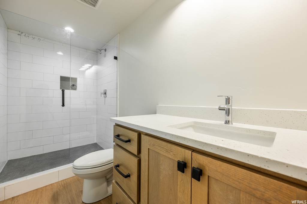 Bathroom with vanity, light parquet floors, and a shower with shower door