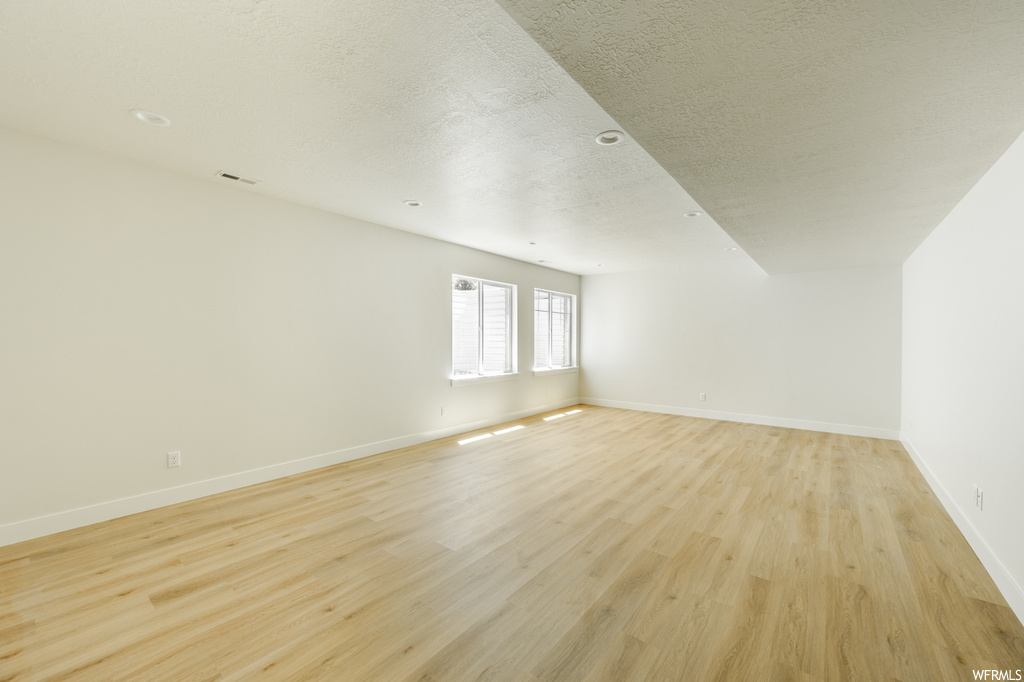 Spare room featuring light hardwood flooring and a textured ceiling