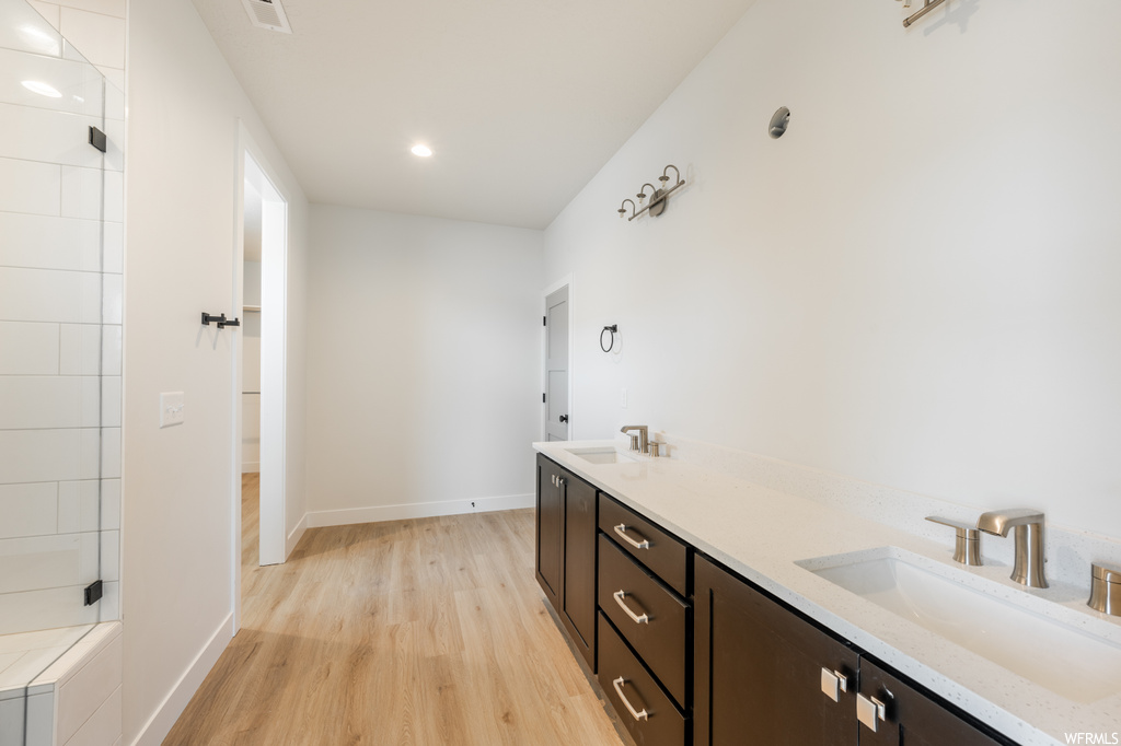 Bathroom with double vanity and light hardwood flooring