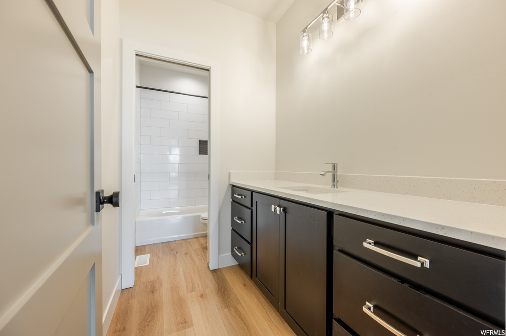 Full bathroom featuring vanity, light hardwood flooring, and tiled shower / bath