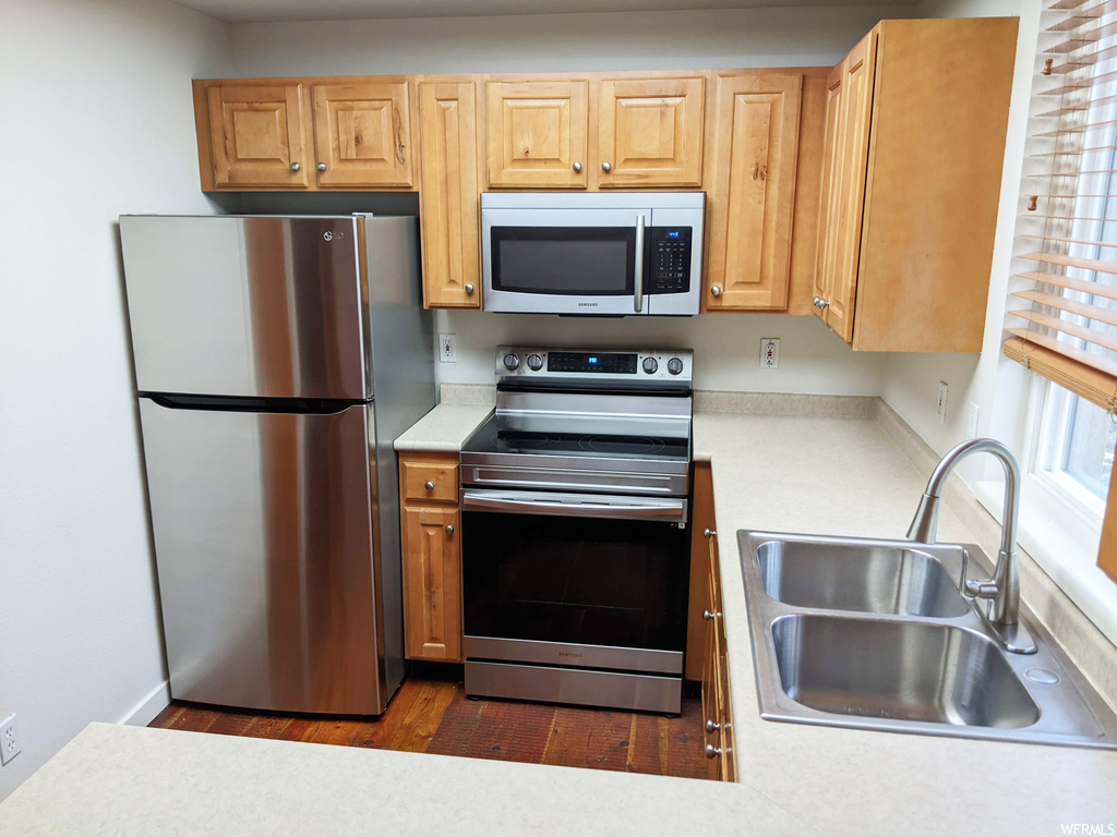 Kitchen featuring stainless steel appliances, brown cabinets, and light hardwood floors