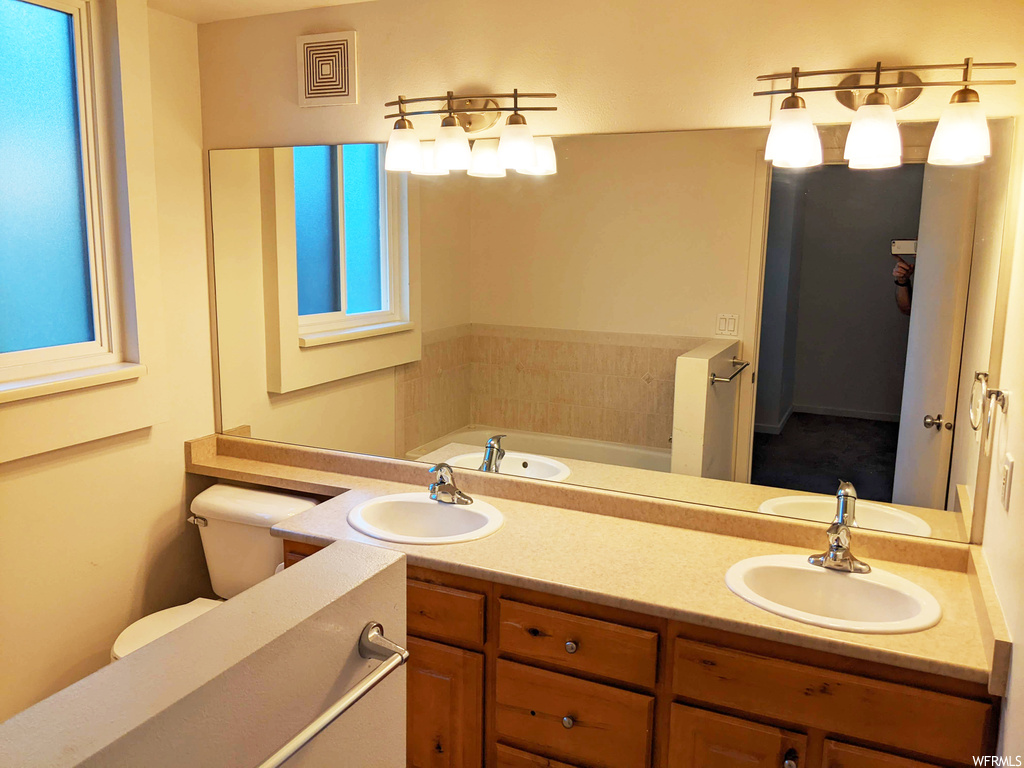 Bathroom featuring double sink vanity, a washtub, and mirror