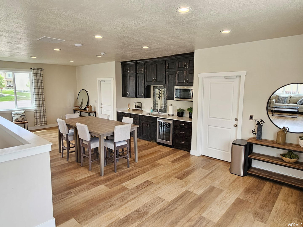 Kitchen featuring dark brown cabinets, light countertops, a textured ceiling, and light hardwood flooring
