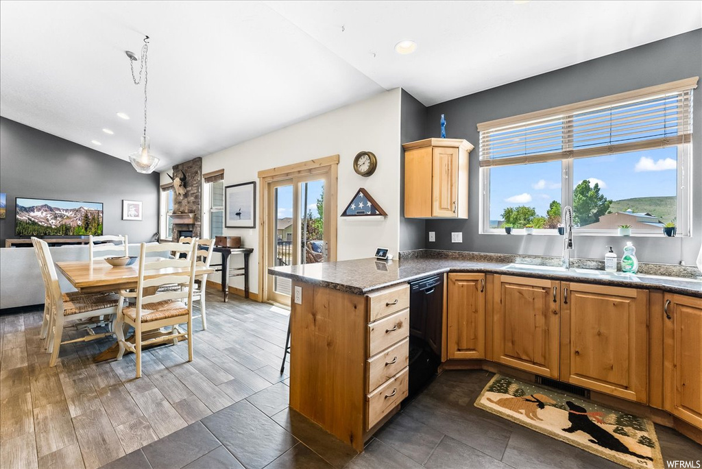 Kitchen with black dishwasher, lofted ceiling, light tile flooring, and brown cabinets