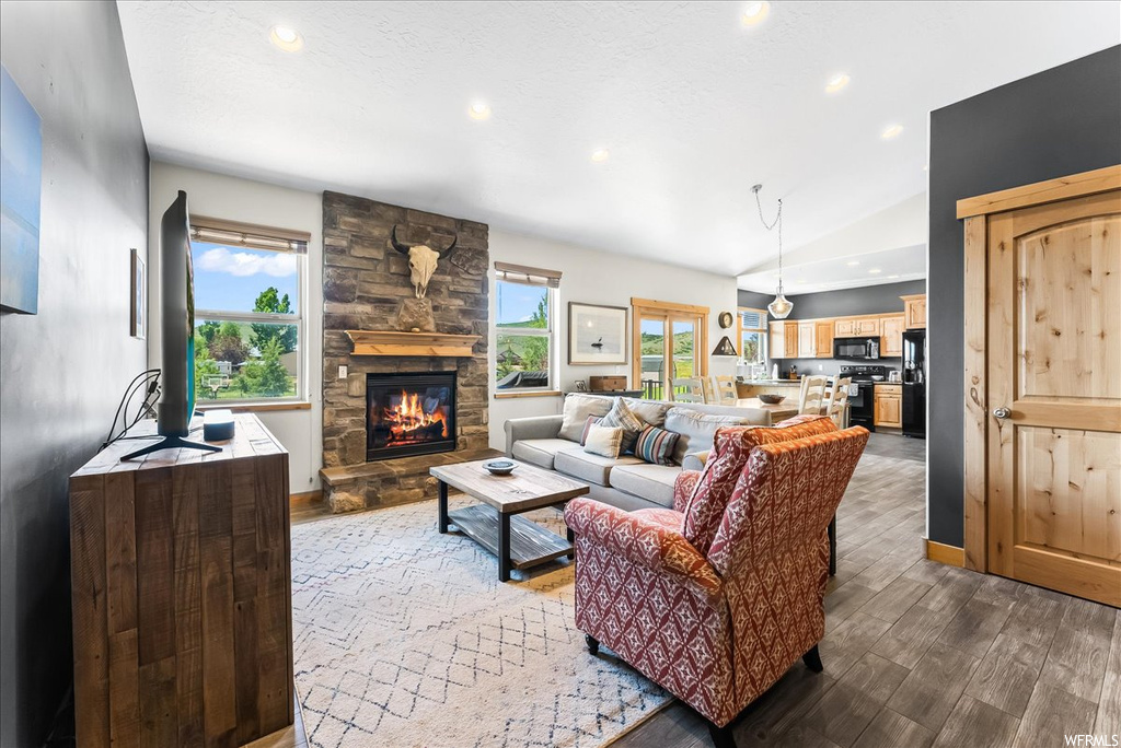 Hardwood floored living room with a fireplace and lofted ceiling