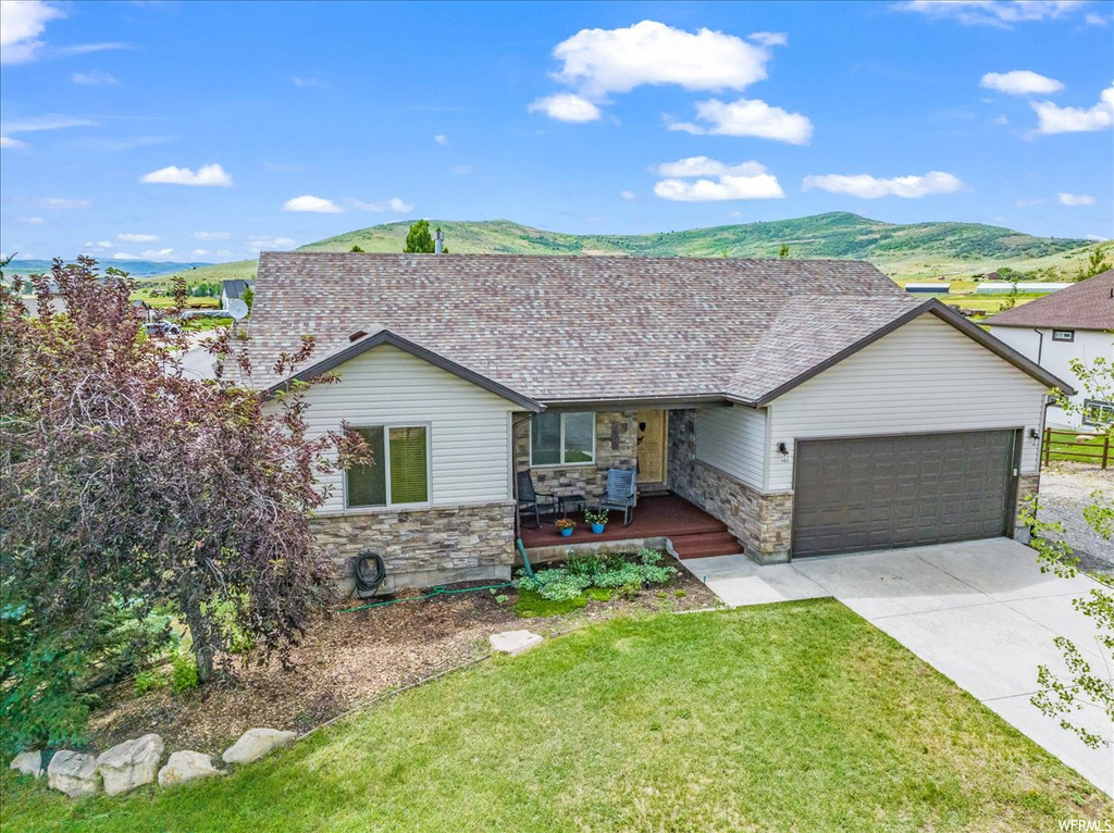 View of front facade with garage, a front yard, and a mountain view