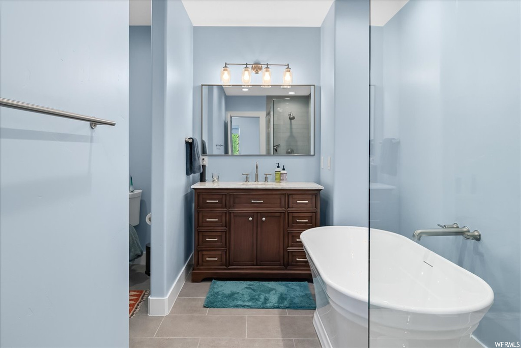 Bathroom with a bathing tub, light tile floors, oversized vanity, and mirror