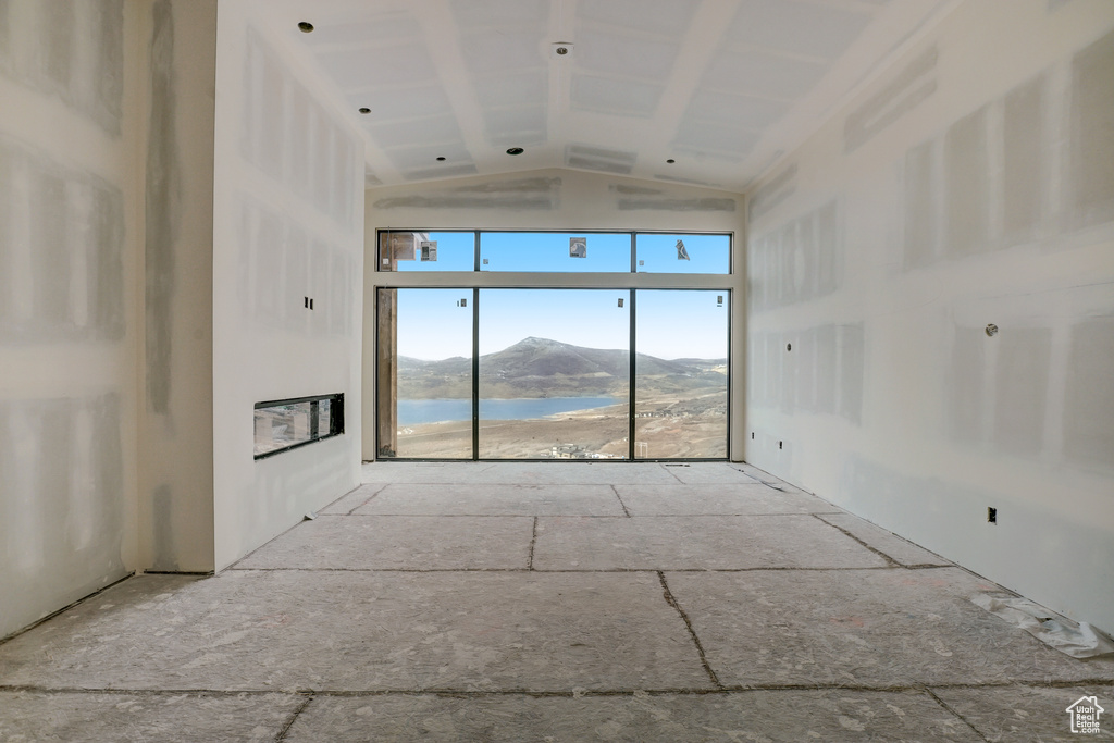 Unfurnished living room featuring a water and mountain view and lofted ceiling