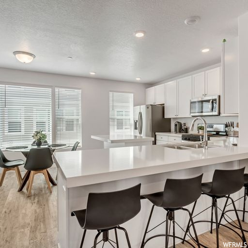 Kitchen featuring white cabinets, range, light countertops, light hardwood floors, a textured ceiling, and a center island