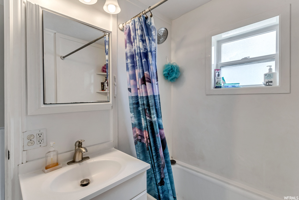 Bathroom with vanity with extensive cabinet space, mirror, and shower / tub combo with curtain