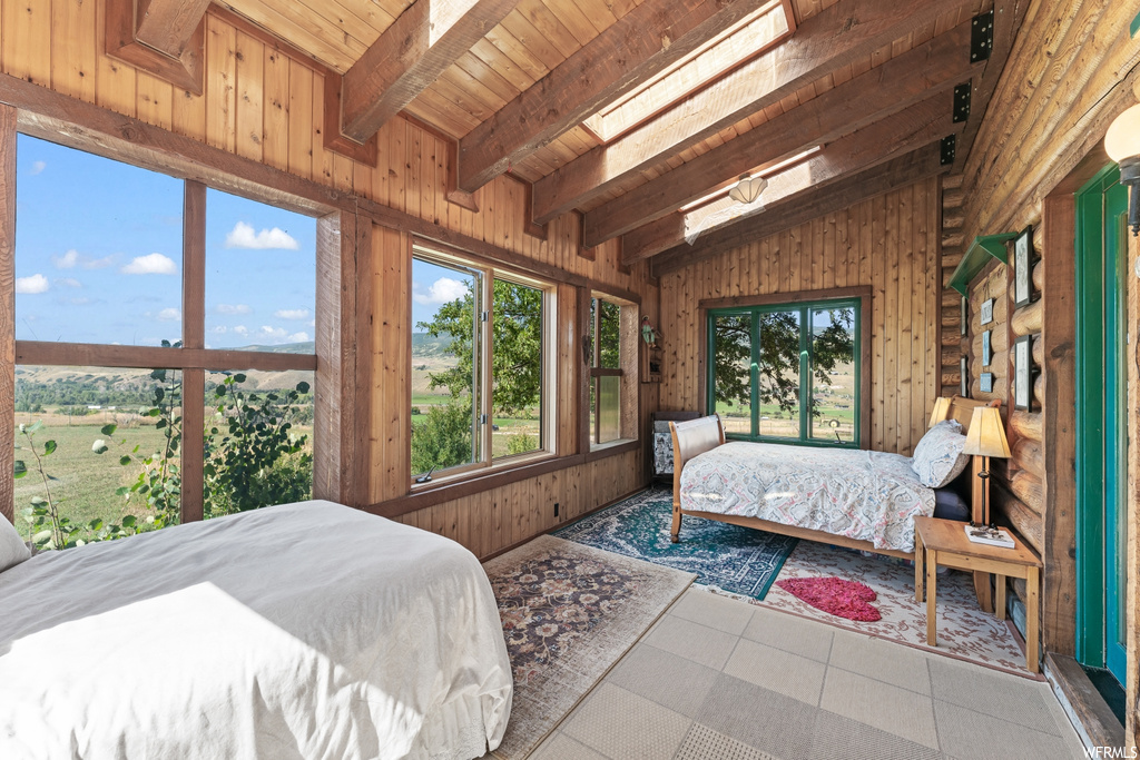 Bedroom with wood walls, wood ceiling, vaulted ceiling with beams, and light tile floors