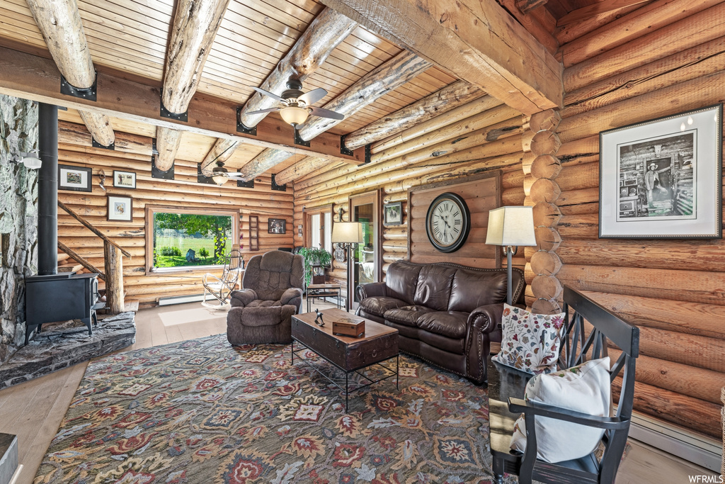 Hardwood floored living room with beam ceiling, log walls, ceiling fan, and wooden ceiling