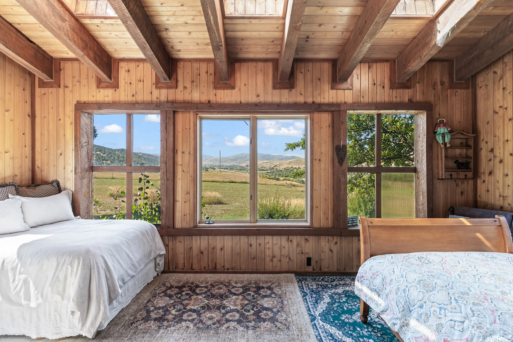 Bedroom with beamed ceiling, wood walls, and wood ceiling