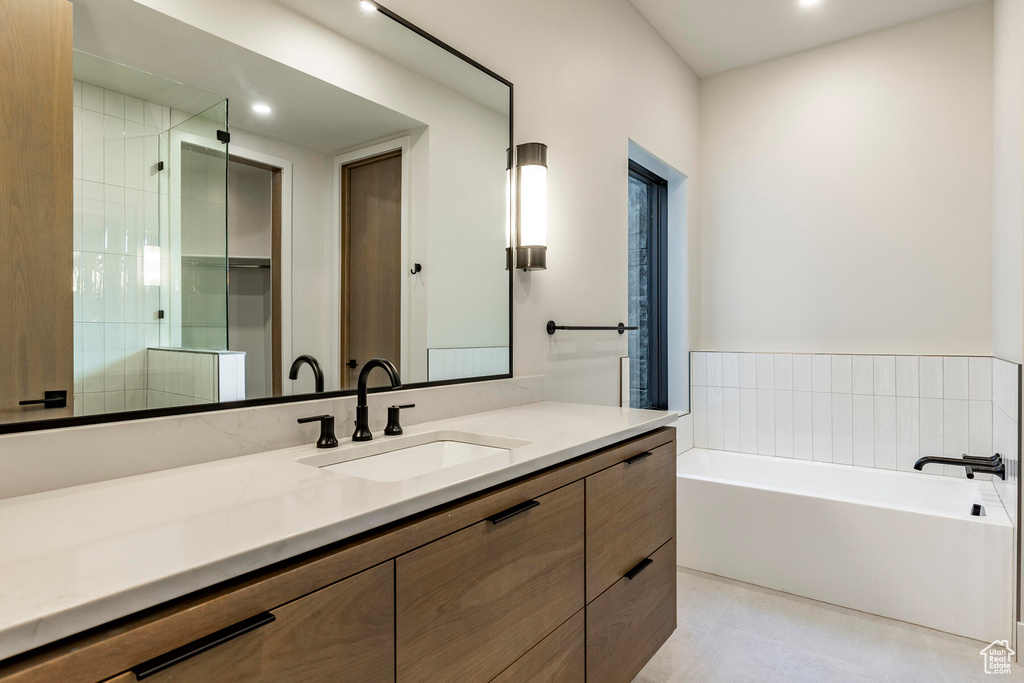 Bathroom featuring tile flooring, vanity, and a bathtub