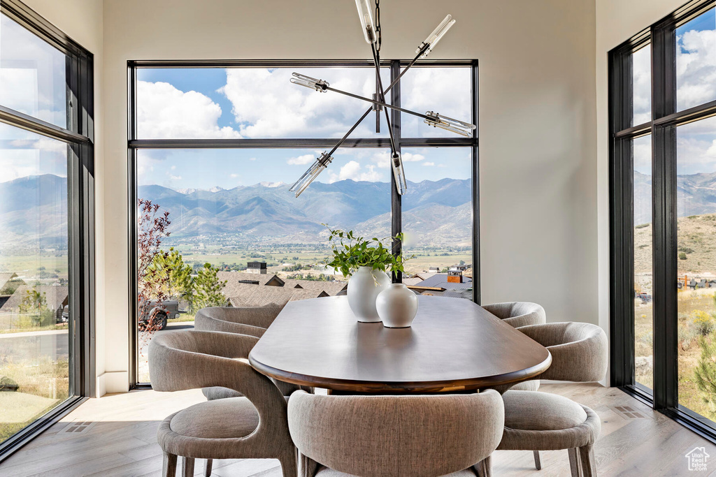 Dining room with light hardwood / wood-style floors, a mountain view, and an inviting chandelier