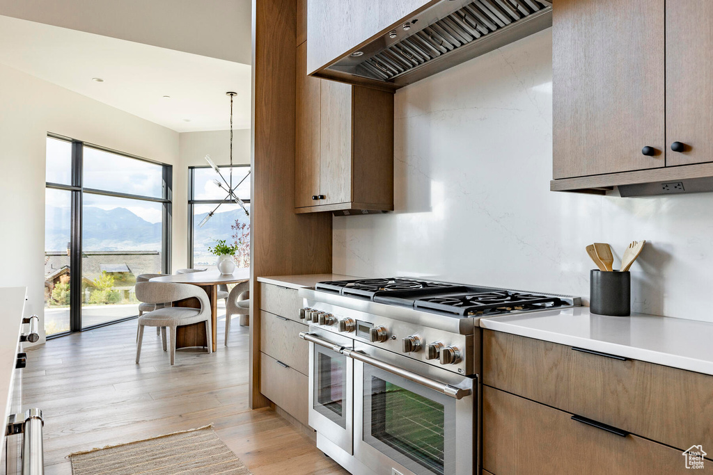 Kitchen featuring range with two ovens, light hardwood / wood-style floors, a mountain view, and custom range hood