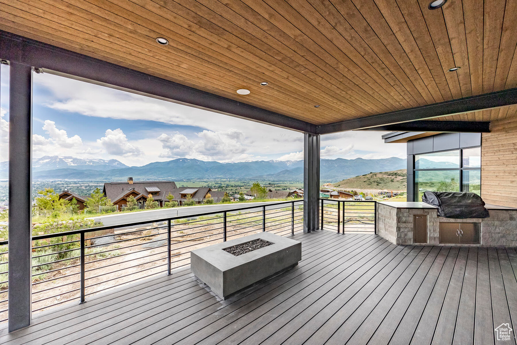 Wooden terrace featuring grilling area, a mountain view, and an outdoor fire pit