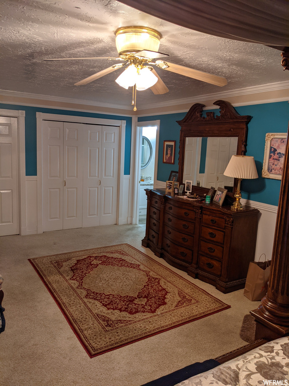 Carpeted bedroom featuring a textured ceiling, ornamental molding, and ceiling fan