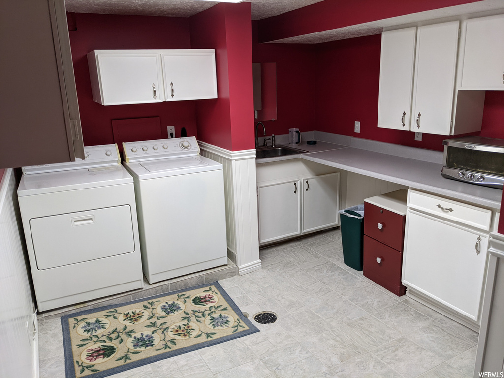 Laundry room featuring light tile flooring, a textured ceiling, and washing machine and dryer