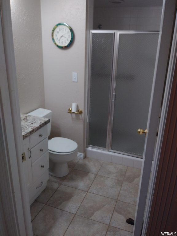 Bathroom featuring vanity, dark tile floors, and an enclosed shower