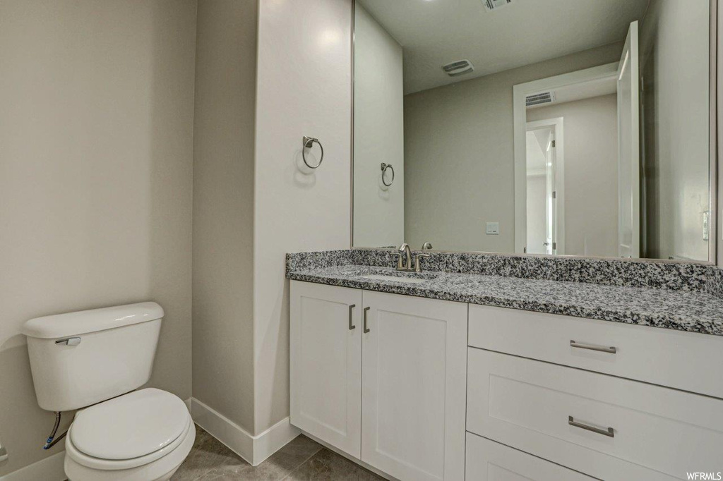 Bathroom featuring dark tile flooring, vanity, and mirror