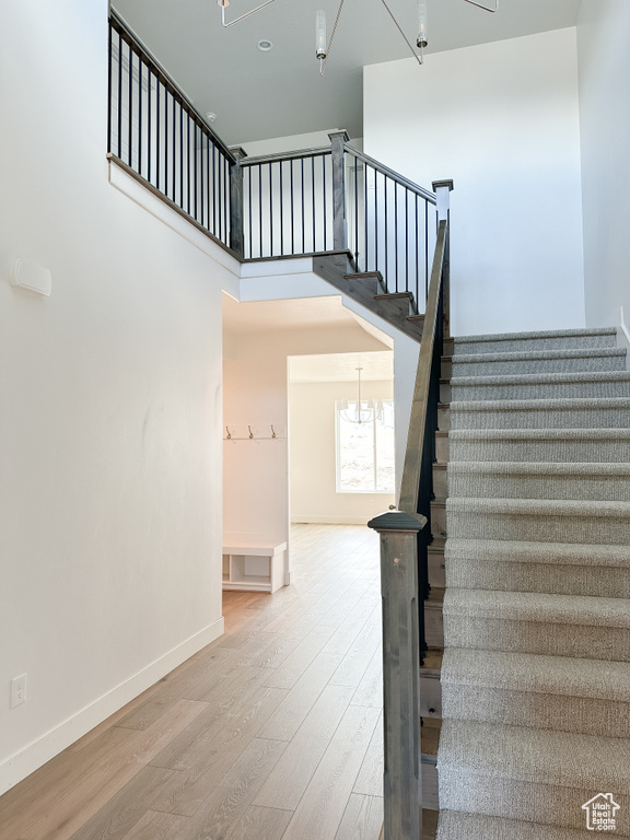 Stairs featuring a notable chandelier and light hardwood / wood-style flooring