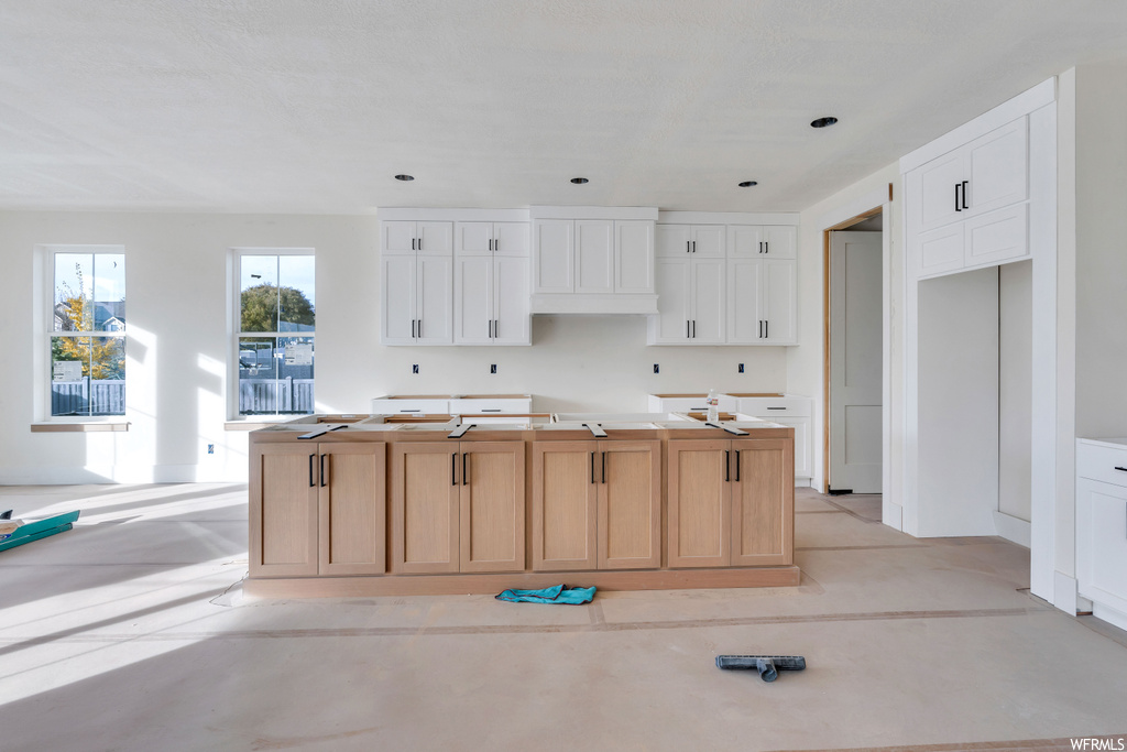 Kitchen featuring a center island with sink and white cabinets