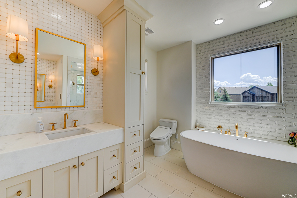 Bathroom featuring toilet, tile flooring, plenty of natural light, and vanity
