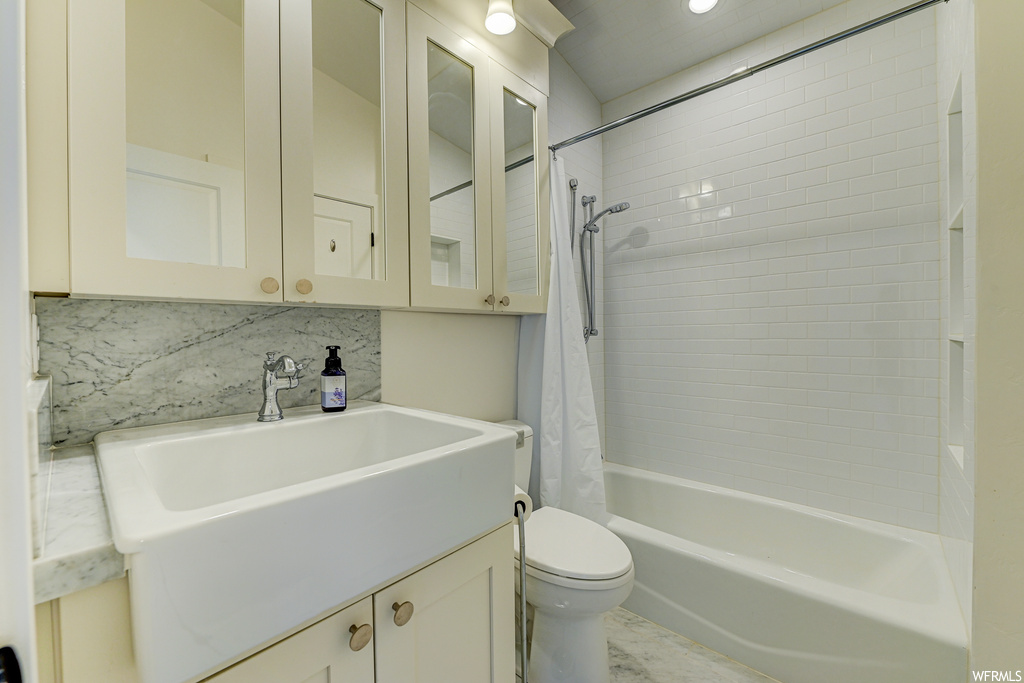 Full bathroom featuring toilet, oversized vanity, tile flooring, shower / tub combo, and backsplash