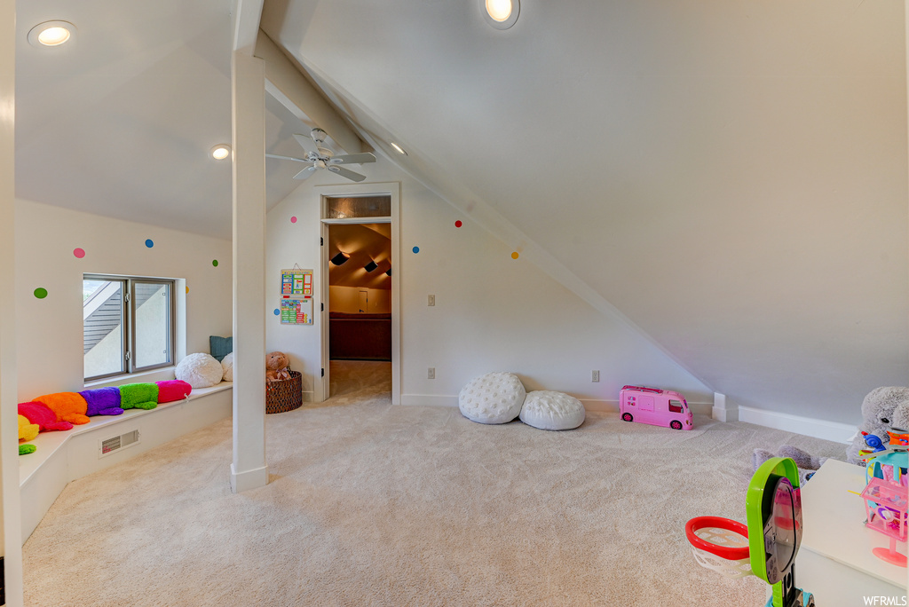Recreation room with lofted ceiling, ceiling fan, and light colored carpet