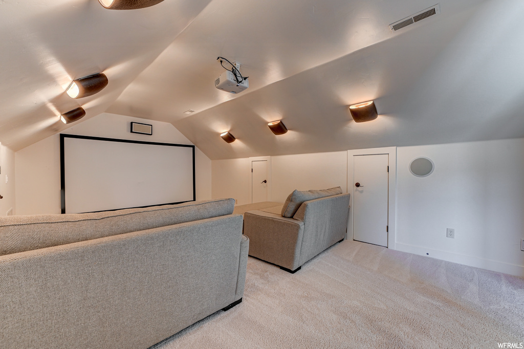 Cinema featuring lofted ceiling and light colored carpet