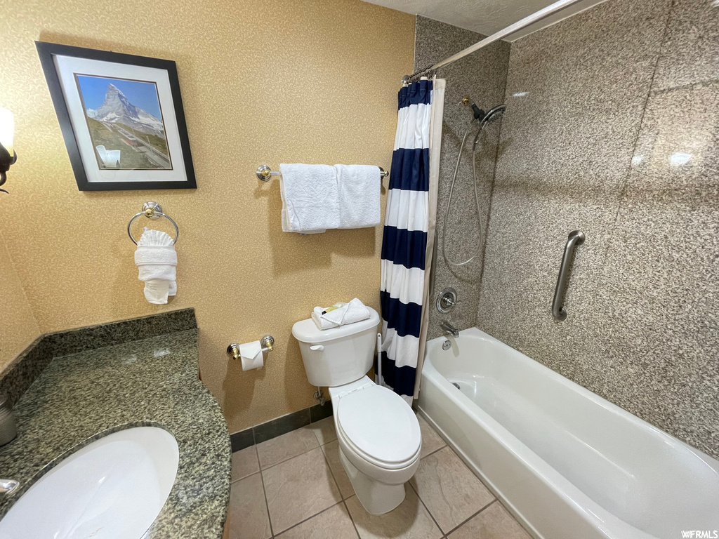 Full bathroom with light tile floors, vanity, and shower / bath combo with shower curtain