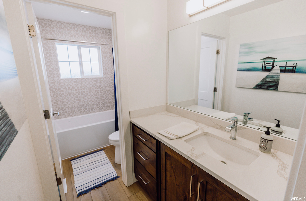 Bathroom with wood-type flooring, vanity, a washtub, and mirror