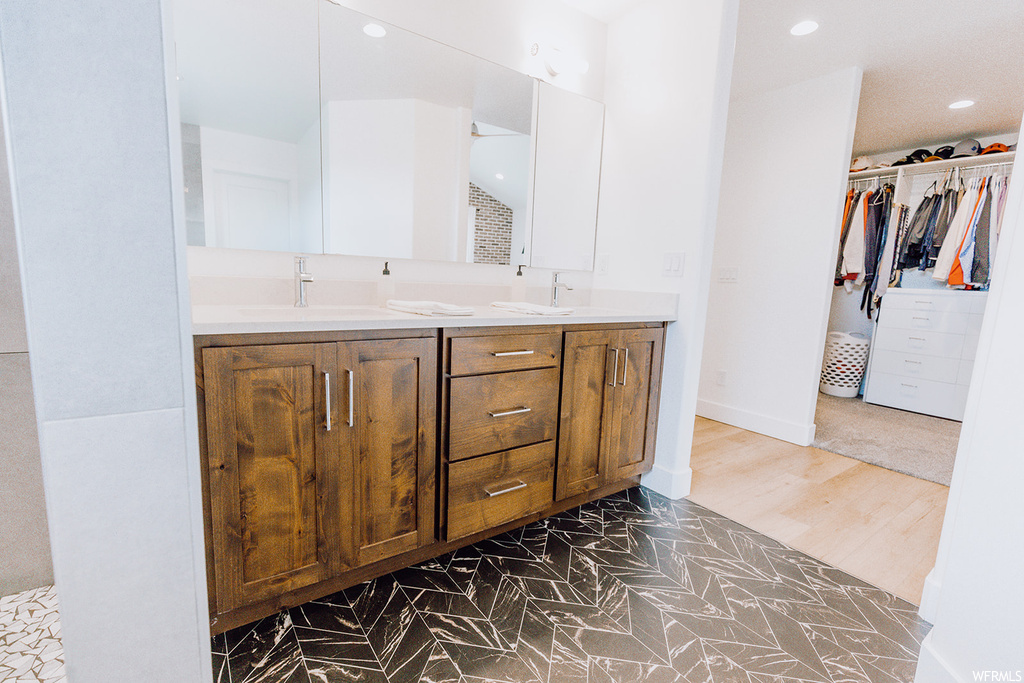 Bathroom featuring double vanity, light hardwood floors, and mirror