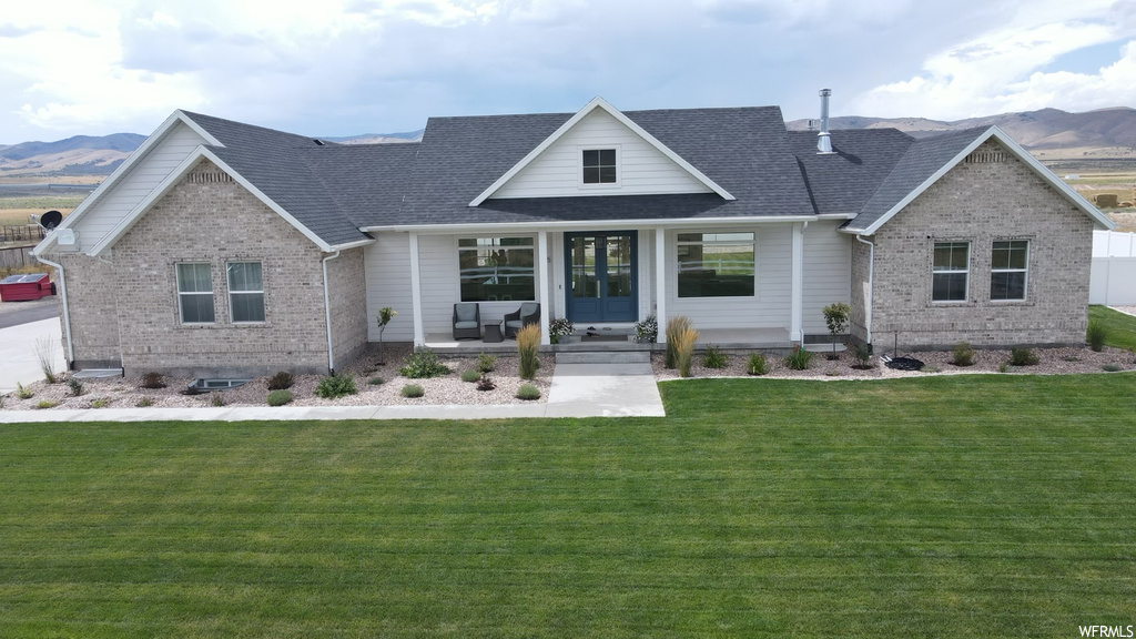 View of front of home with a patio, a front lawn, and a mountain view