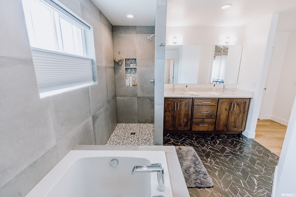 Bathroom with double large sink vanity, mirror, light tile floors, and shower with separate bathtub