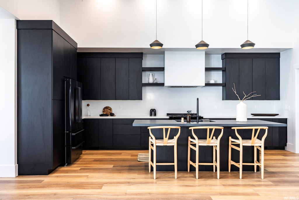 Kitchen with dark brown cabinets, a center island, and light hardwood floors