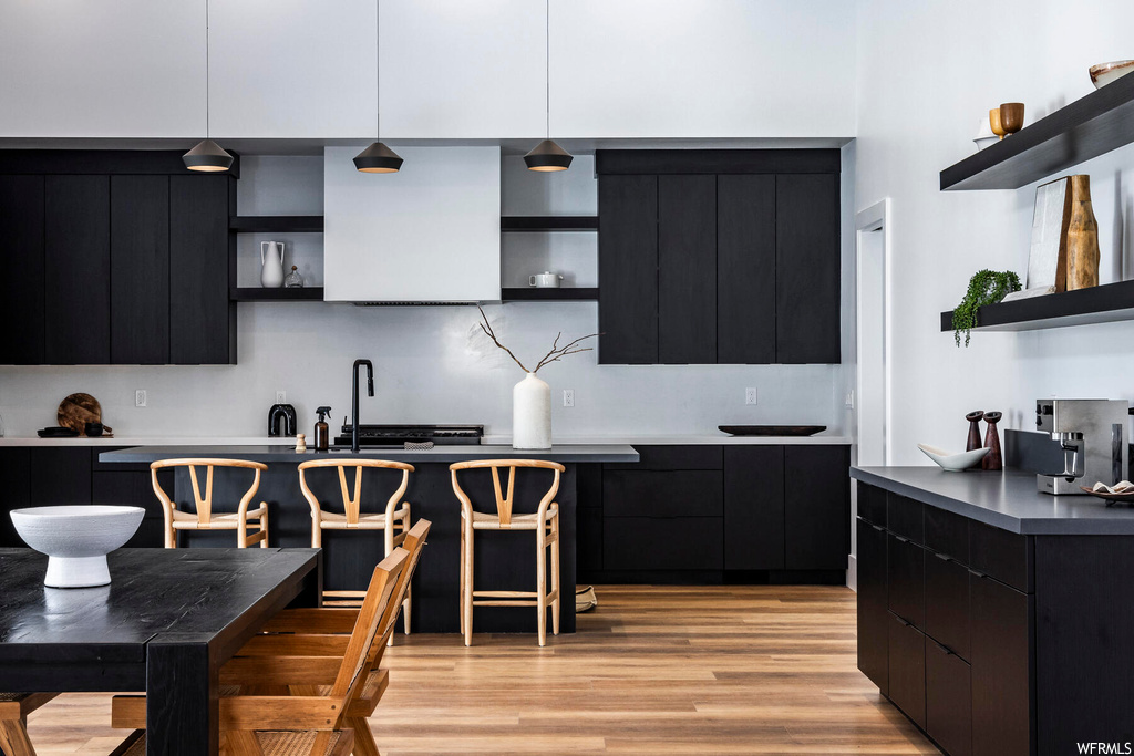 Kitchen with dark brown cabinets, light parquet floors, and backsplash