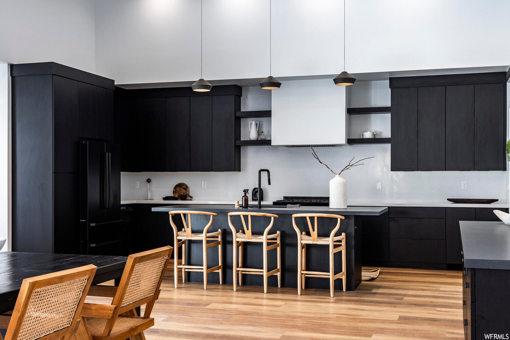Kitchen with dark brown cabinets, backsplash, a center island, and light hardwood floors