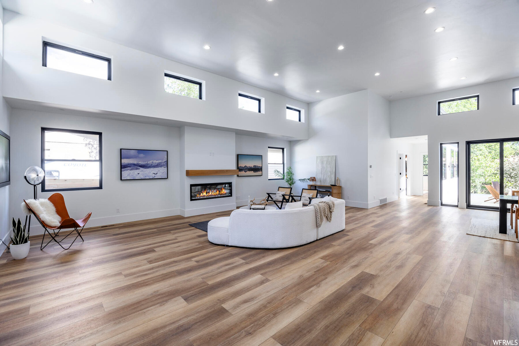 Living room featuring a healthy amount of sunlight, a high ceiling, and light hardwood floors