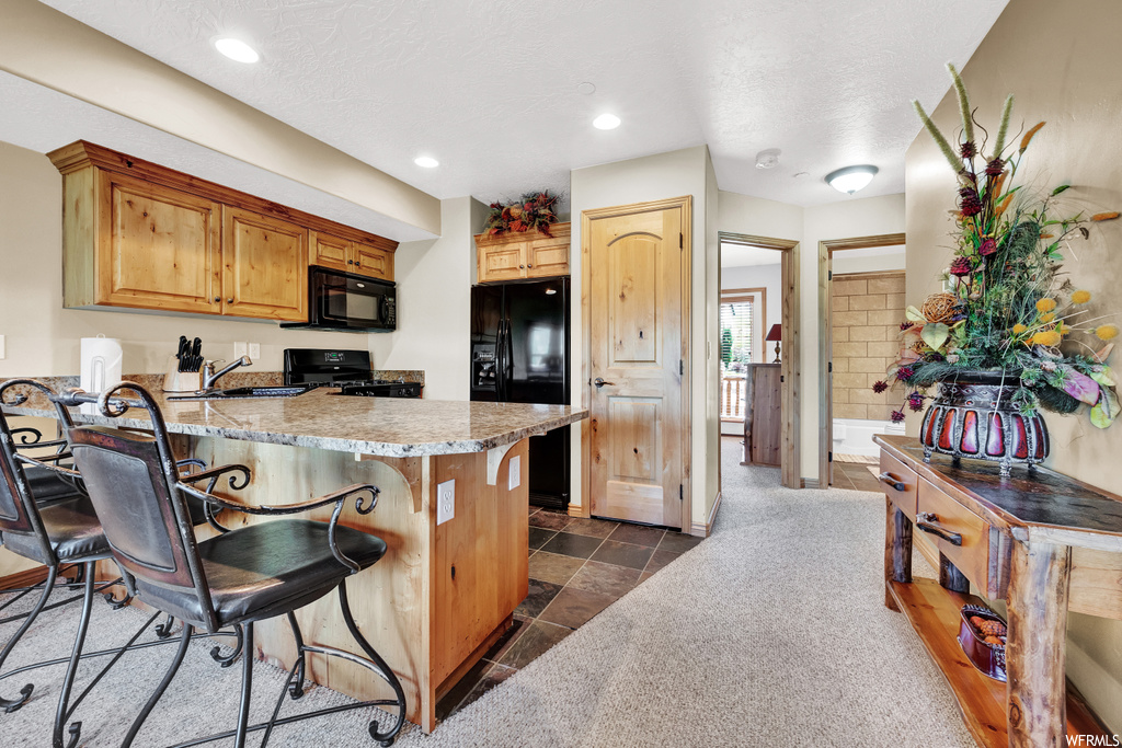Kitchen with light granite-like countertops, range, brown cabinets, and light carpet