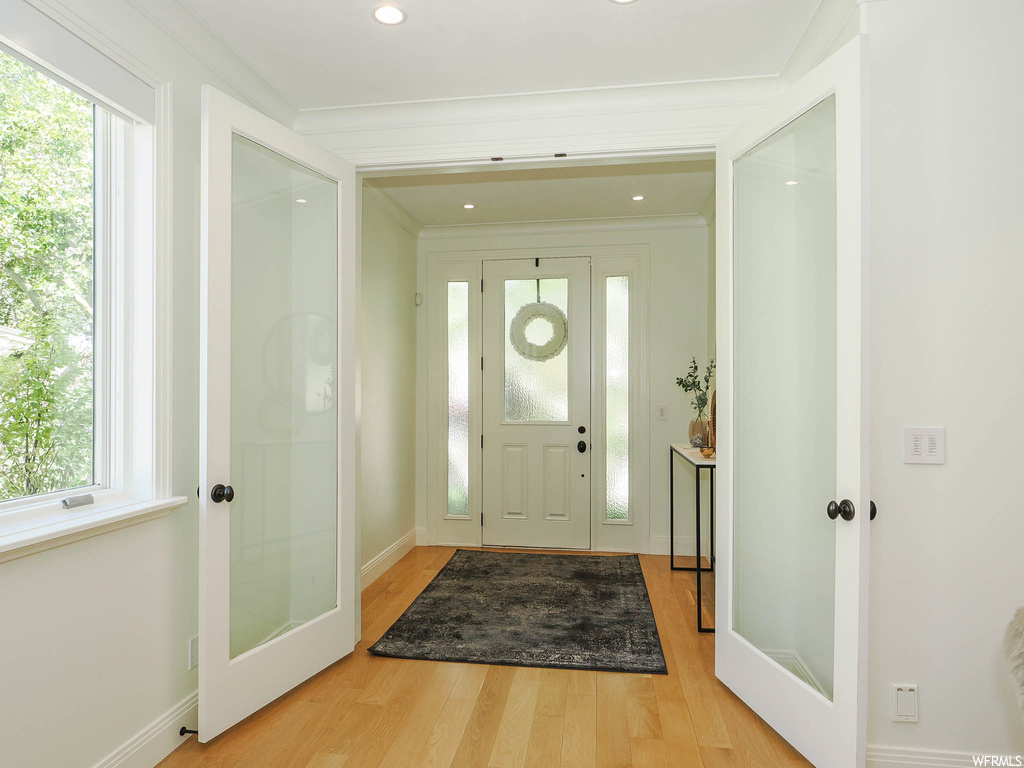 Hardwood floored foyer featuring crown molding and a wealth of natural light
