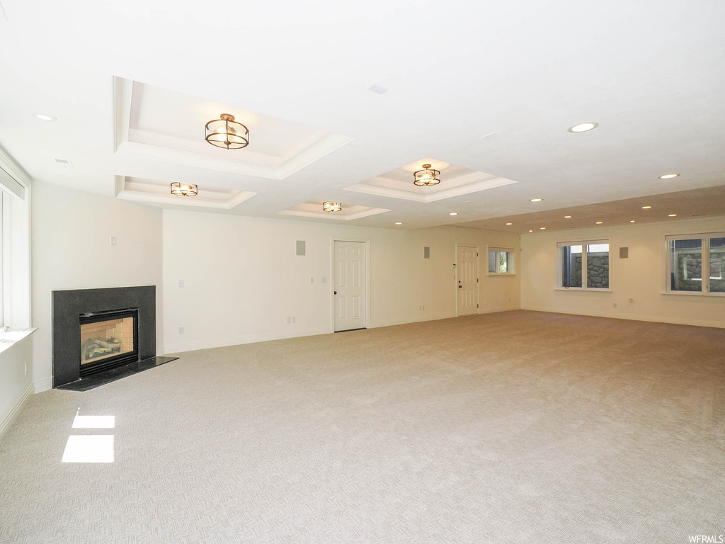 Carpeted living room with a fireplace and a tray ceiling