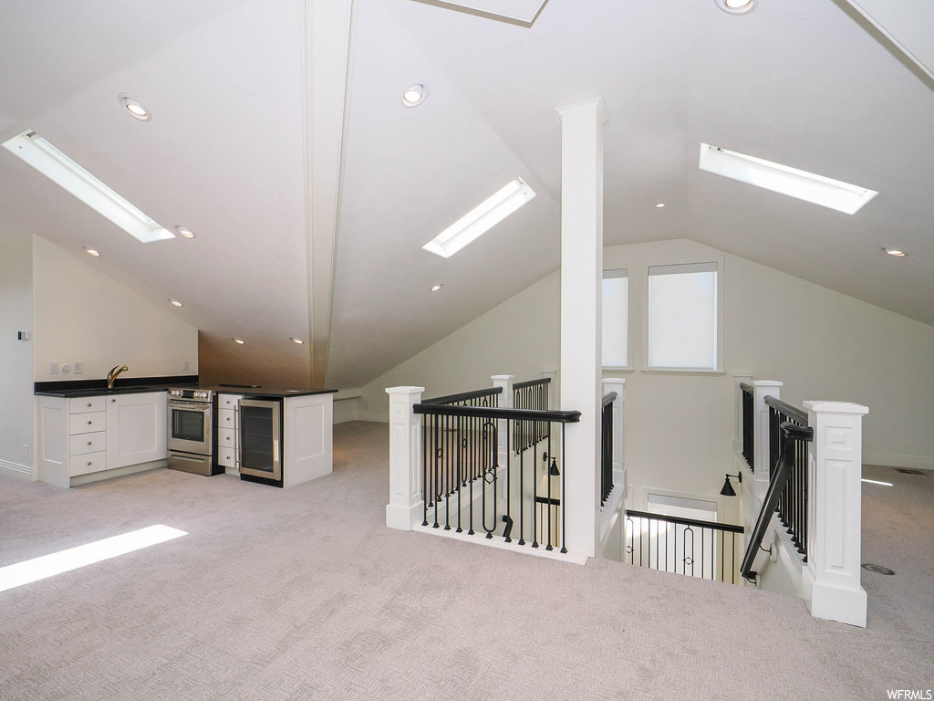 Additional living space featuring light carpet and vaulted ceiling with skylight