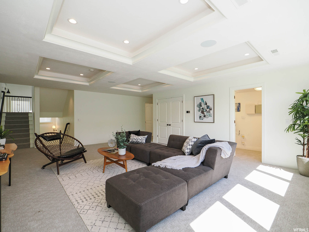 Carpeted living room featuring coffered ceiling and a tray ceiling