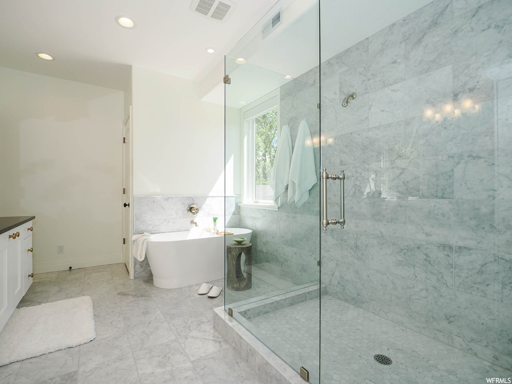 Bathroom with separate shower and tub, light tile floors, tile walls, and vanity
