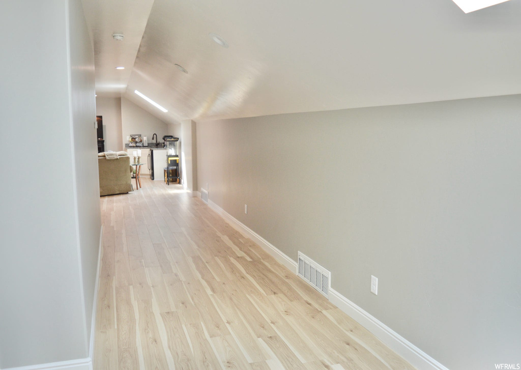 Hallway featuring light parquet floors and lofted ceiling