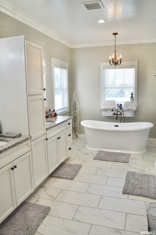 Bathroom featuring ornamental molding, vanity, light tile flooring, and a tub