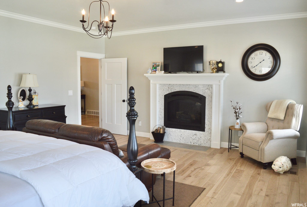 Bedroom with crown molding, a fireplace, and light hardwood flooring