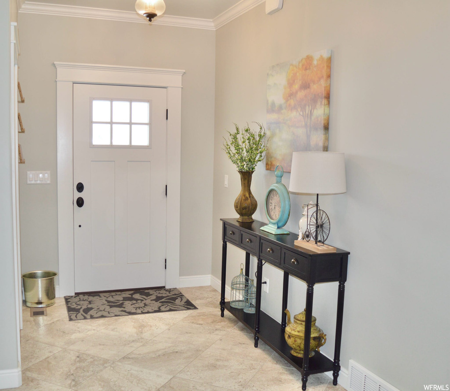 Foyer featuring ornamental molding and light tile flooring